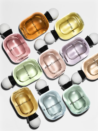 A collection of colorful perfume bottles with spherical caps arranged on a white background, showcasing a variety of scents and hues.