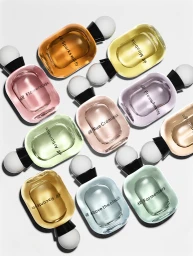 An overhead view of ten colourful glass perfume bottles with white caps arranged against a bright white background.
