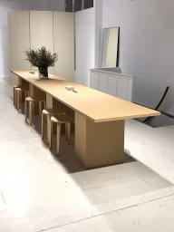 Long minimalist wooden table with matching stools and a glass vase of dried flowers styled by Eleonora Succi