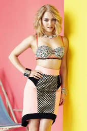 Blonde woman wearing patterned strapless crop top and peach skirt against pink and yellow studio backdrop