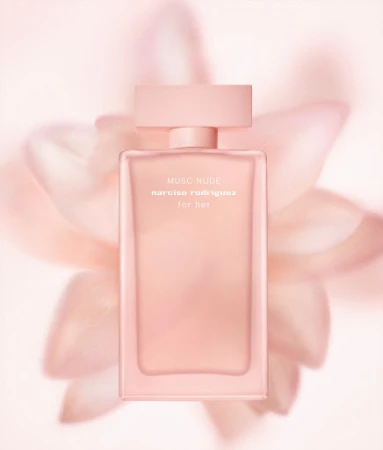 Close-up product shot of a peach-toned Narciso Rodriguez Musc Nude perfume bottle set against a blurred pale peach floral backdrop.