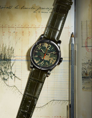 Wristwatch with camouflage dial and olive green leather strap resting on antique ledger next to silver pen, close-up studio shot.