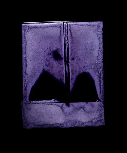 Abstract photograph of a rectangular object in shades of purple and black, creating a minimalist and atmospheric composition.