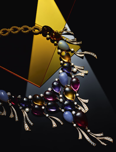 Elegant gemstone necklace featuring a blend of colorful, translucent stones and diamond accents against a geometric, high-contrast backdrop.