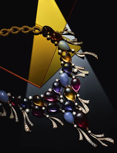 Elegant gemstone necklace featuring a blend of colorful, translucent stones and diamond accents against a geometric, high-contrast backdrop.
