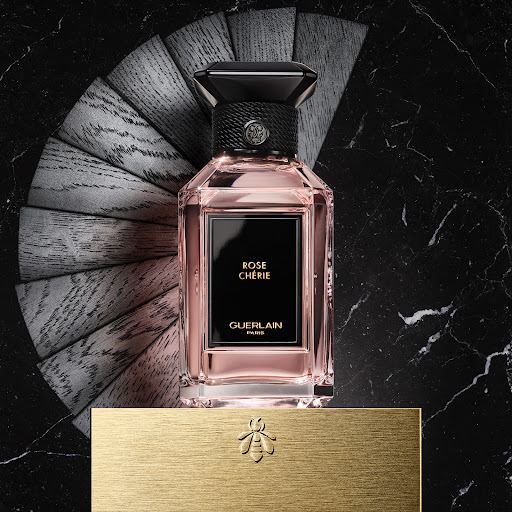 Elegant pink perfume bottle on a gold stand, featuring geometric design, contrasting textures, and luxurious marble background details.