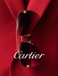 Cartier sunglasses with gold frames and tinted lenses resting on a textured red blazer