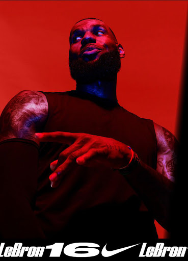 Close-up shot of LeBron James in athletic wear under red and blue lighting, showcasing his tattoos and muscular physique, Nike logo visible.