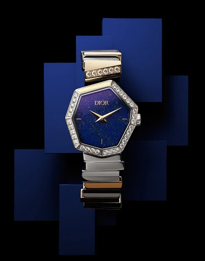 Elegant Dior women's wristwatch with a unique blue dial, diamond bezel, and two-tone gold and silver band on a geometric blue background.