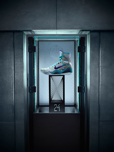 Nike boxing shoe is displayed inside an illuminated display case with geometric patterned backing and dark metal framing.
