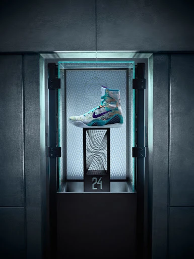 Nike boxing shoe is displayed inside an illuminated display case with geometric patterned backing and dark metal framing.