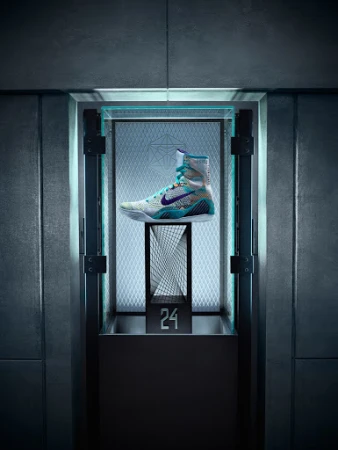 Nike boxing shoe is displayed inside an illuminated display case with geometric patterned backing and dark metal framing.