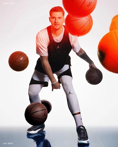Professional portrait of a basketball player dribbling a ball in a light studio setting with several basketballs surrounding him.