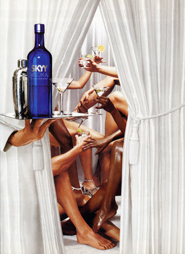 Skyy Vodka ad features a bottle and cocktail shaker on a tray held by a white-gloved hand, plus several people holding cocktails between curtains.