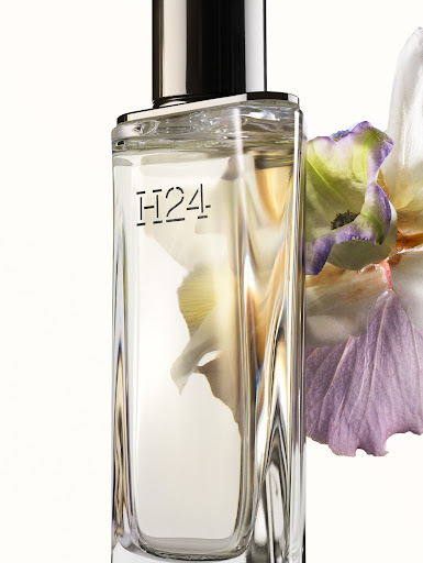 Close up product photograph of a rectangular glass perfume bottle with metallic cap and floral styling by Jefferson Fouquet
