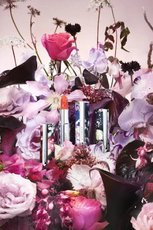 Floral arrangement featuring Givenchy lipstick in silver tubes with floral designs, showcasing beauty and fashion in an indoor studio setting.