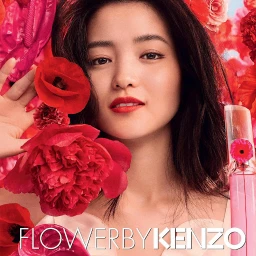 Close-up portrait of an East Asian woman surrounded by vibrant red poppies holding a perfume bottle.
