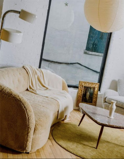 Interior design featuring a tan sofa with a throw blanket, set on a wooden floor with a modern coffee table and minimalist decor.