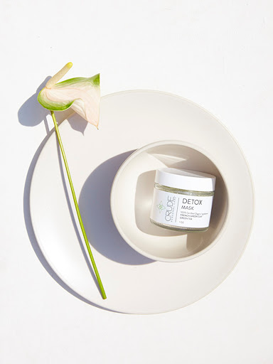 Product shot of a jar of detox mask on a white plate with a calla lily. Perfect for skincare, beauty, or spa concepts.