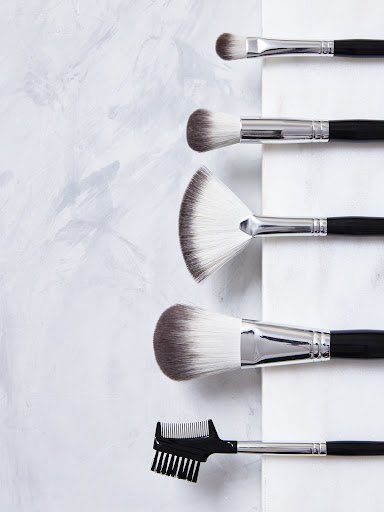 Overhead shot of black-handled makeup brush set arranged vertically on a white and grey marble surface, beauty and cosmetics concept.