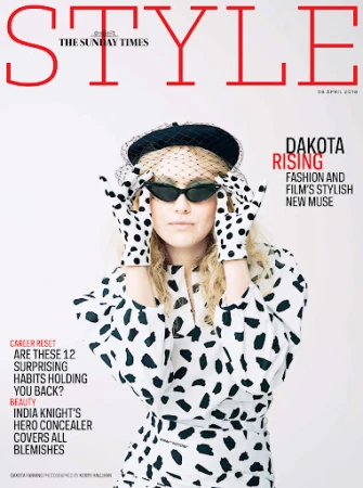 Dakota Fanning wearing a polka dot outfit and black beret with a veil against a plain white background.