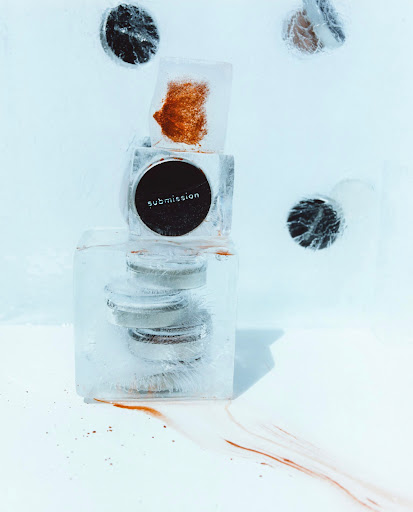 A stack of cosmetics encased in clear ice blocks, set against a bright white background, highlighting beauty and frozen aesthetics.