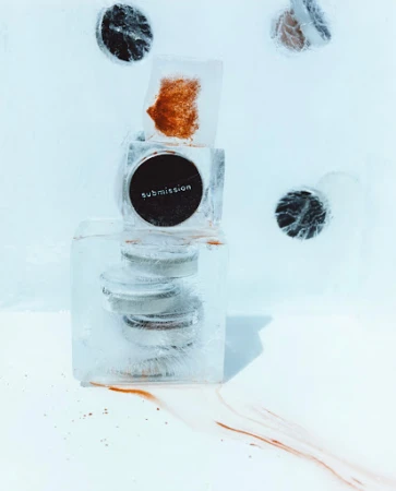 A stack of cosmetics encased in clear ice blocks, set against a bright white background, highlighting beauty and frozen aesthetics.