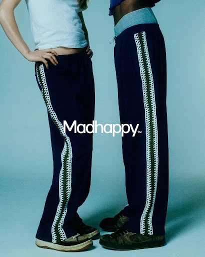 Two figures display navy sweatpants with white crochet stripes, paired with sneakers, against a cool blue studio backdrop. Madhappy logo.