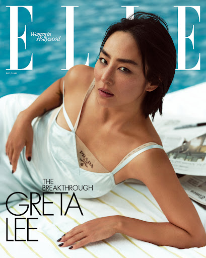 Elle magazine cover featuring Greta Lee reclining by a pool, wearing a slip dress. Elle logo and headlines are visible. Fashion shot.
