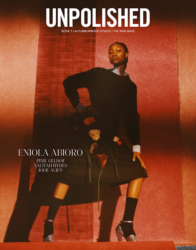 Fashion magazine cover featuring a Black woman in a dark outfit and glittery heeled boots, posing in front of an orange backdrop.