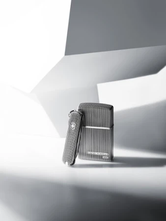 Still life studio shot of a metal Swiss Army knife and a lighter with vertical striped patterns against a white and grey geometric background.