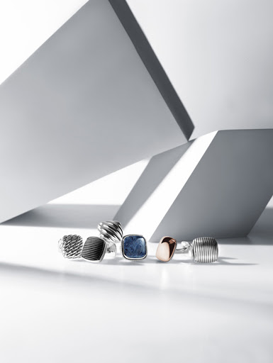Set design still life featuring multiple silver and gemstone rings arranged on a white surface