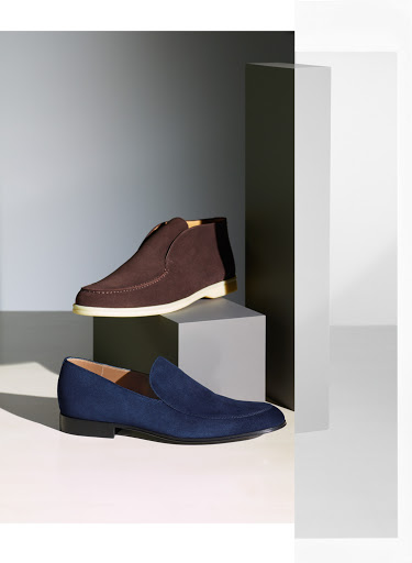 Studio shot showcasing a brown leather boot and a navy blue suede loafer, elegantly arranged on geometric white and grey platforms.