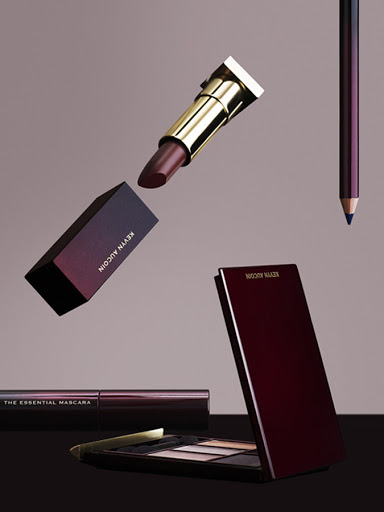Cosmetics still life: Lipstick, mascara, eye shadow palette, and eye pencil arranged against a neutral background in a beauty product shot.