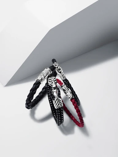 Three woven bracelets with silver leaf clasps in black, red, and dotted black, displayed on a neutral white background.