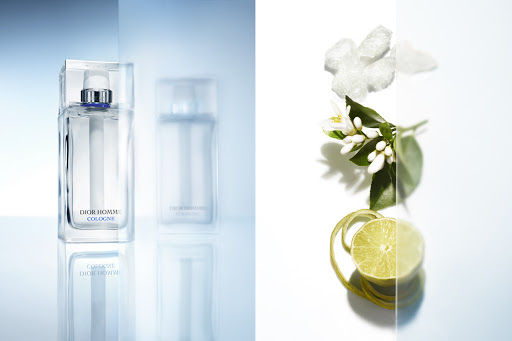 Dior Homme Cologne fragrance with citrus fruit and flowers on a white background, showcasing its fresh and aromatic composition.