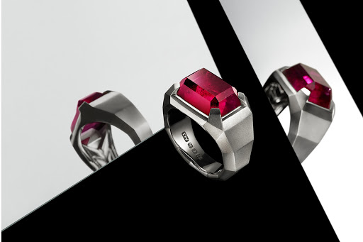 Three jewelry rings featuring a silver band and a rectangular ruby stone, arranged against a contrasting black and white background.