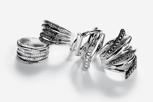Close-up studio shot of four intricately designed silver rings with black and white gemstone accents, displayed on a clean white surface.