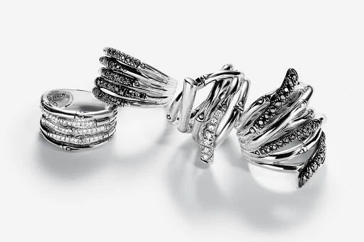 Close-up studio shot of four intricately designed silver rings with black and white gemstone accents, displayed on a clean white surface.