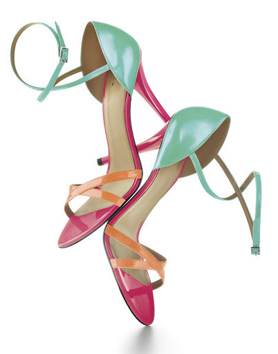 Elevated studio shot of a pair of color-blocked high-heeled sandals with pink, orange, and turquoise patent leather straps.