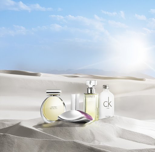 Calvin Klein fragrance bottles displayed in a desert landscape against a clear blue sky, promoting beauty and elegance.