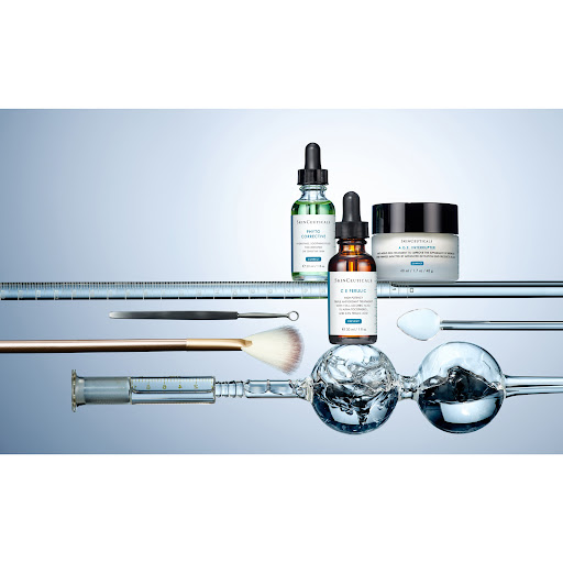Cosmetic products including bottles and a jar are displayed with applicators on a reflective surface against a light blue background.