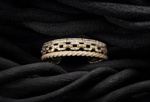 Close-up of two gold and diamond bracelets on black fabric showcasing luxury jewellery, fine craftsmanship, and elegant design.
