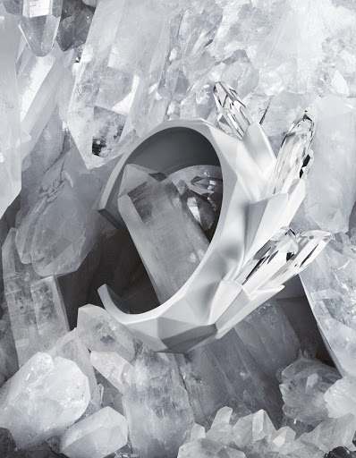 Abstract composition with a sculptural white geometric bracelet set against a background of large quartz crystals, creating a modern design.