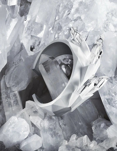Abstract composition with a sculptural white geometric bracelet set against a background of large quartz crystals, creating a modern design.