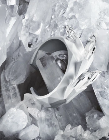 Abstract composition with a sculptural white geometric bracelet set against a background of large quartz crystals, creating a modern design.