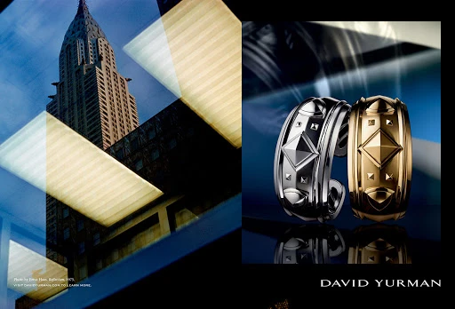 Luxury jewelry advertisement featuring two cuff bracelets with angular gemstone designs, posed against a blurred architectural backdrop.