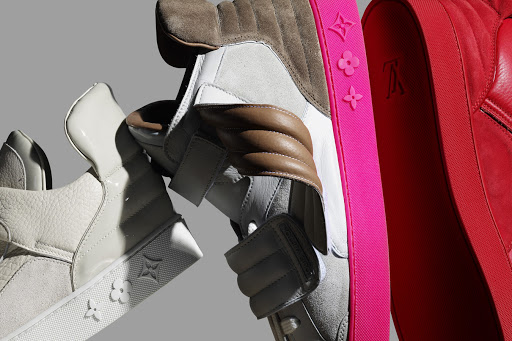 A close-up studio shot showcases three luxury sneakers, each featuring distinct colors and textures, arranged against a neutral gray backdrop.