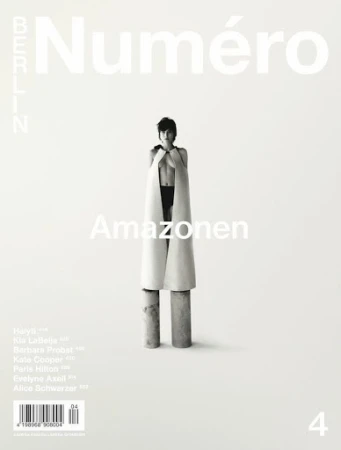 Black-and-white fashion magazine cover featuring a female model in avant-garde apparel, standing on cylinders, with the magazine's title at the top.