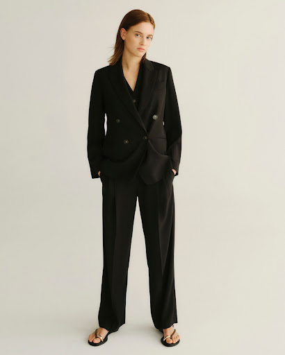 Model standing in a black double-breasted suit against a plain white background